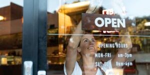 Happy business owner hanging an open sign at a cafe