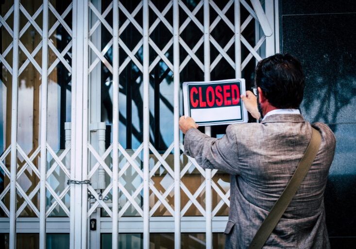 Business man closing a business activity putting closed sign on the door