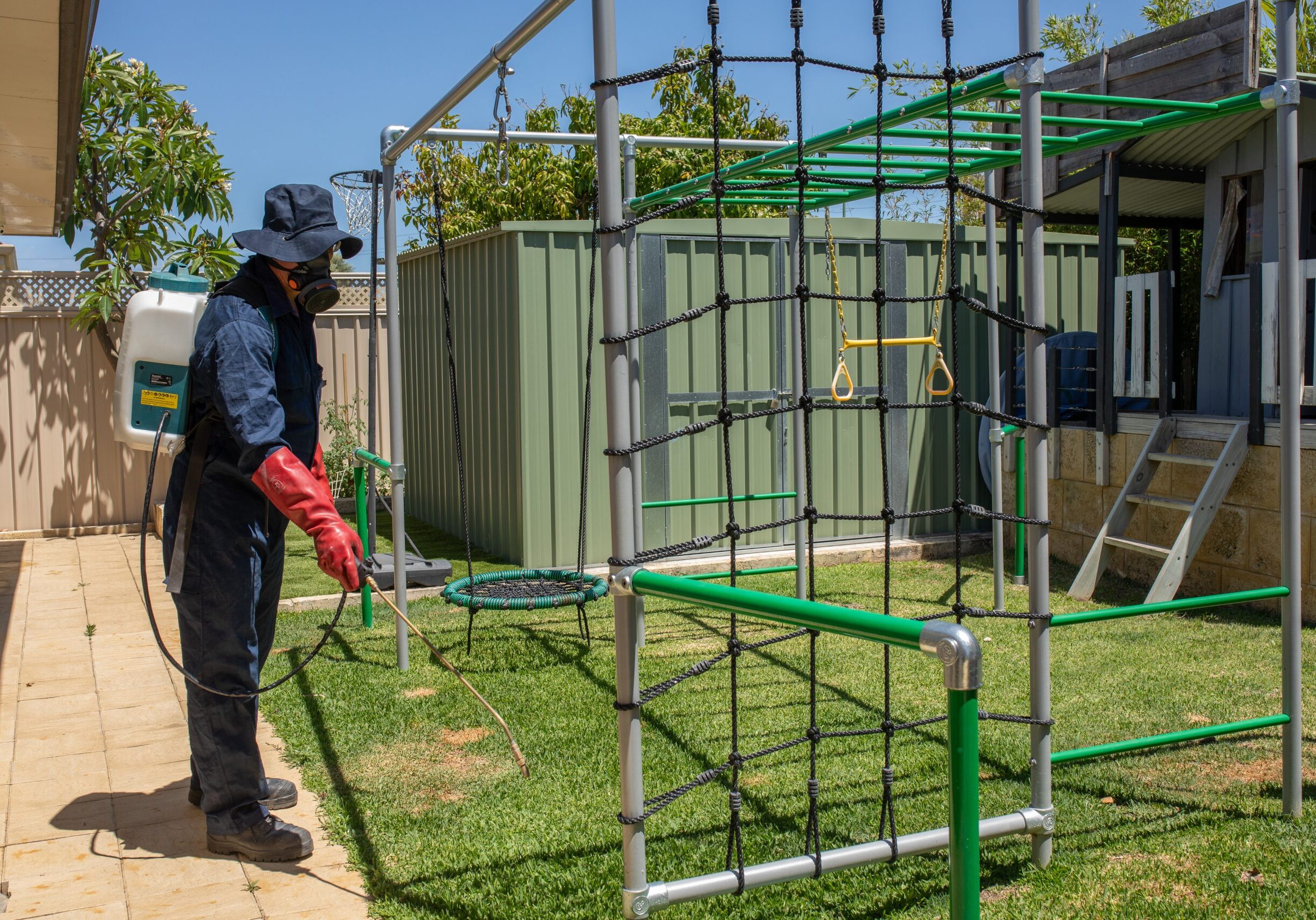 Person spraying chemicals on backyard playground.